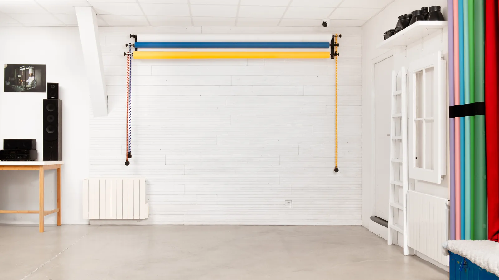 Le mur du Studio Traditionnel, trois rouleaux de fond papier enroulés et la sono du studio